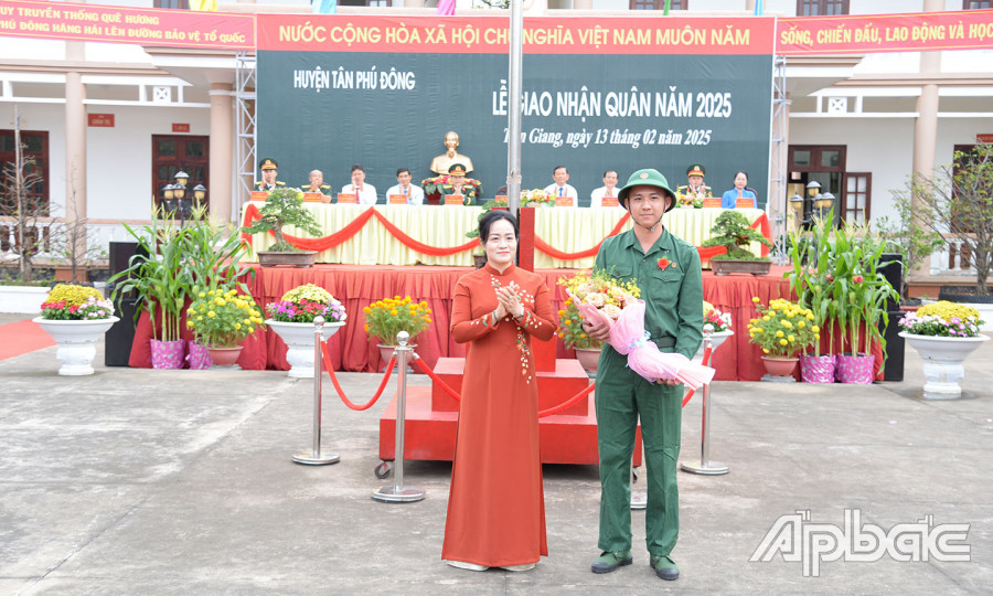 Đồng chí Nguyễn Hải Trâm tặng hoa cho tân binh Nguyễn Chí Linh, đại diện 58 thanh niên huyện Tân Phú Đông lên đường nhập ngũ.