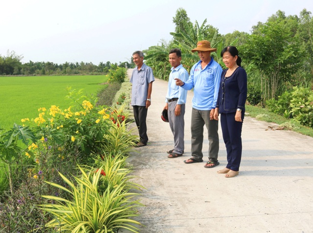 Ông Trần Văn Khoái (đội nón) chia sẻ trồng hoa, cây xanh dọc tuyến đường có phần đất ông tự nguyện hiến.